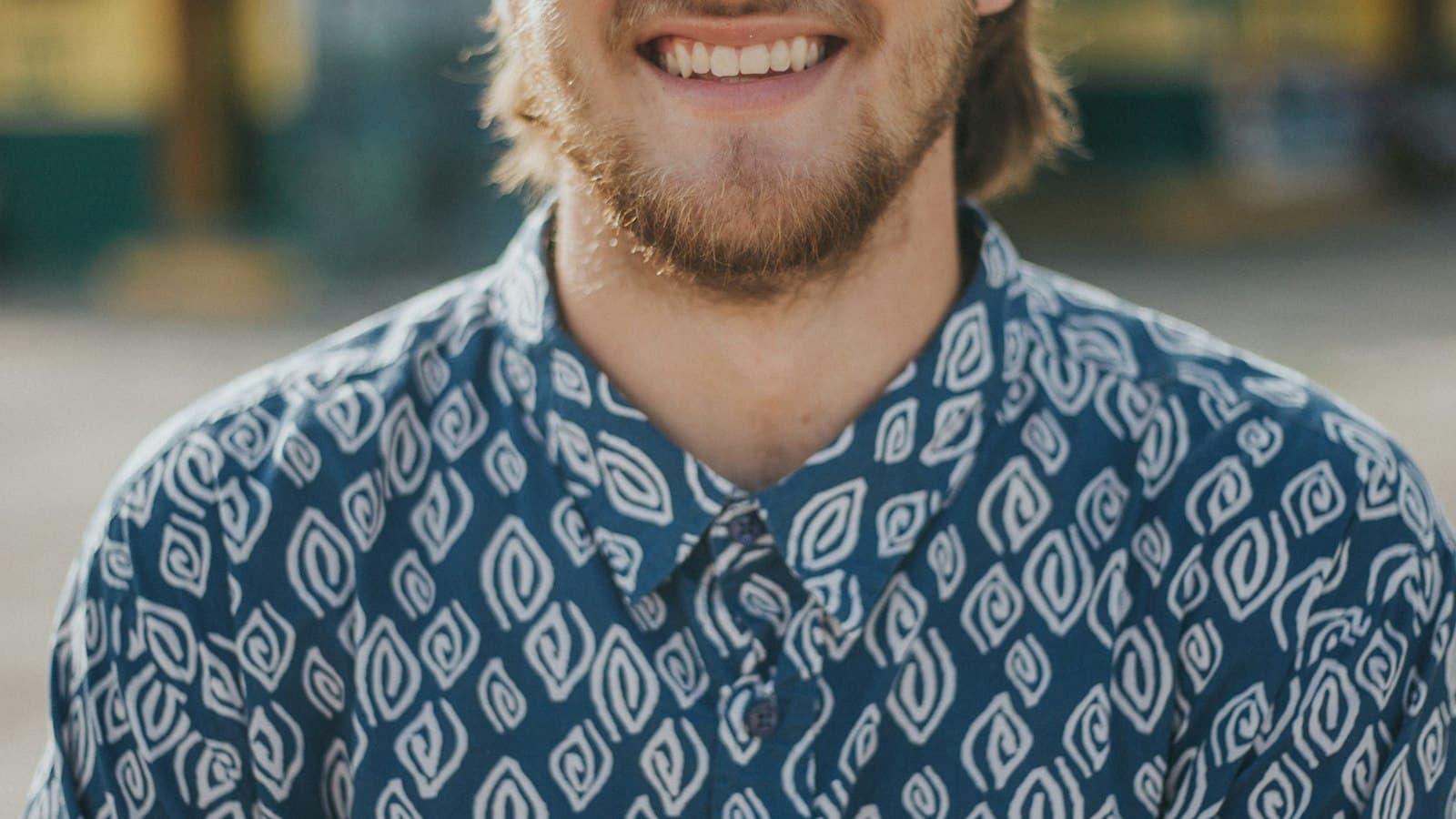 A man with a warm smile in a patterned shirt