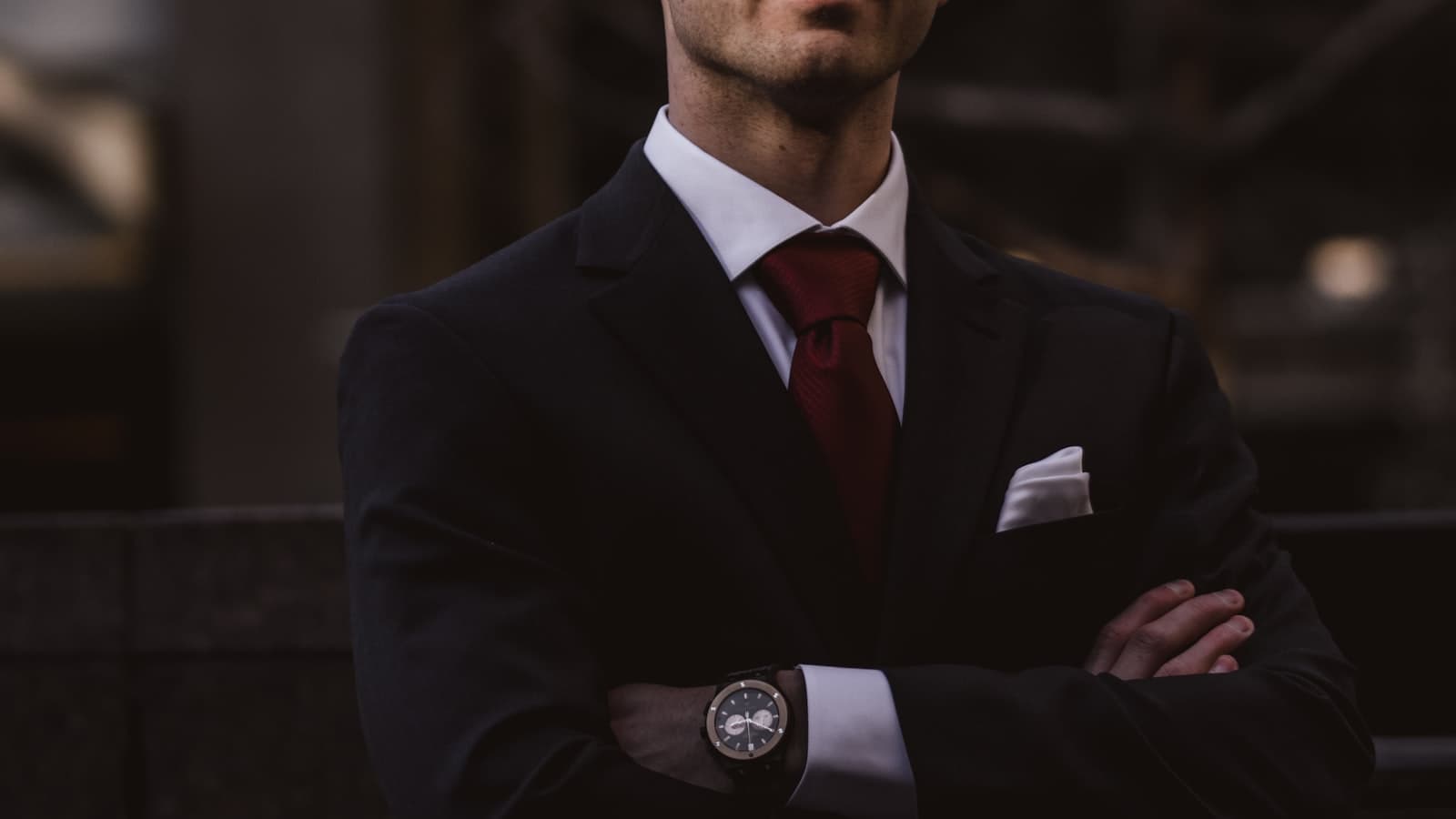 Man in a suit with a red tie, arms folded