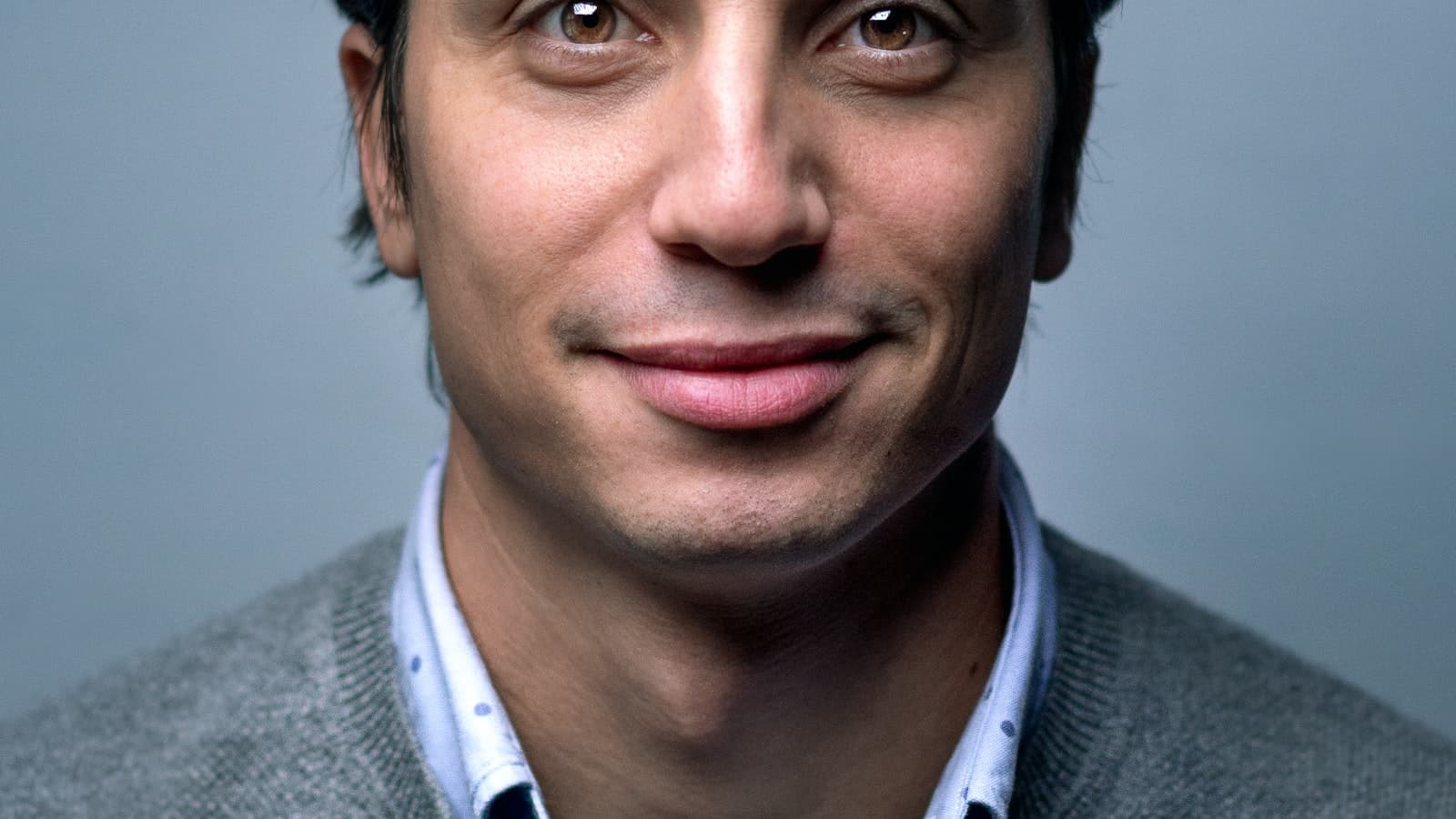 Man in a grey sweater smiling at the camera